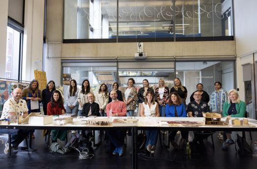 The judges sit at a long table, behind them stand the students who participated in the Liberty and Vita challenge.