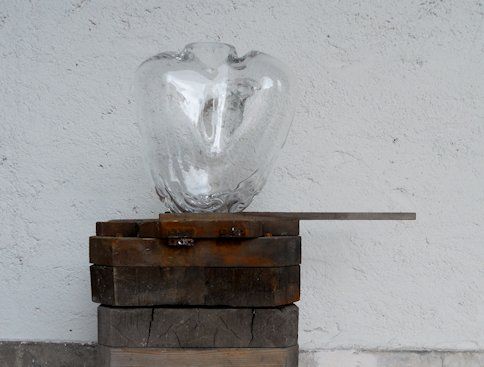 A picture of a piece of art made from glass standing on a plinth. The glass is shaped roughly like a human heart.